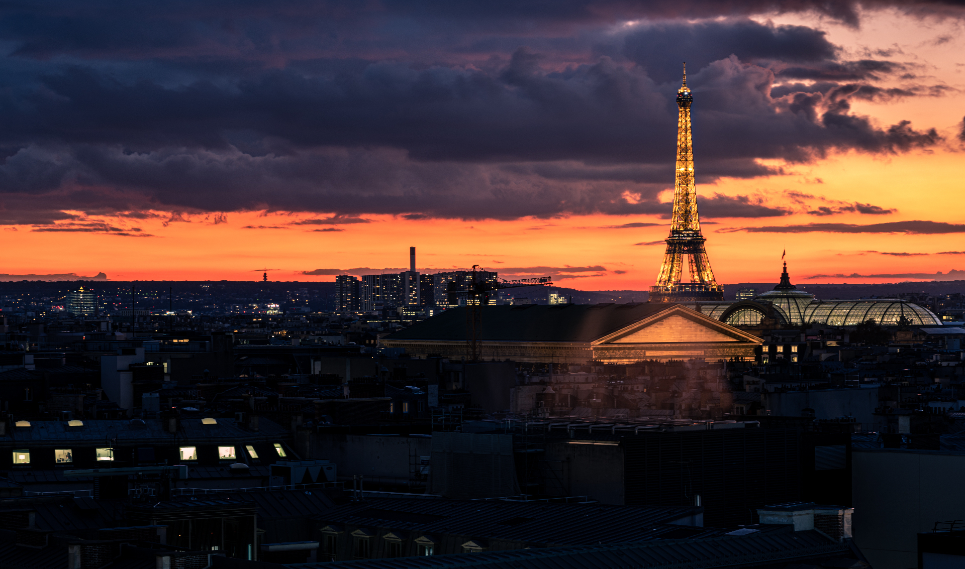 Tour Eiffel scintillante sur ciel de feu, toits de Paris
