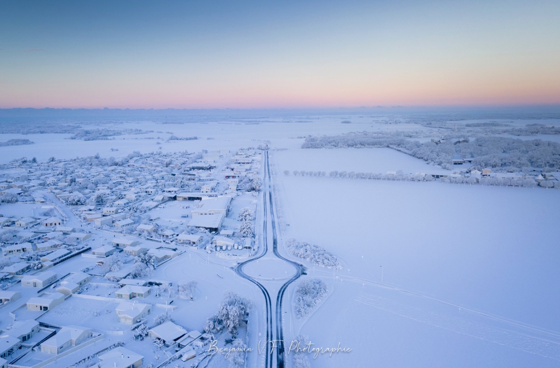 Rond-point enneigé et village givré vus du ciel à l'aube