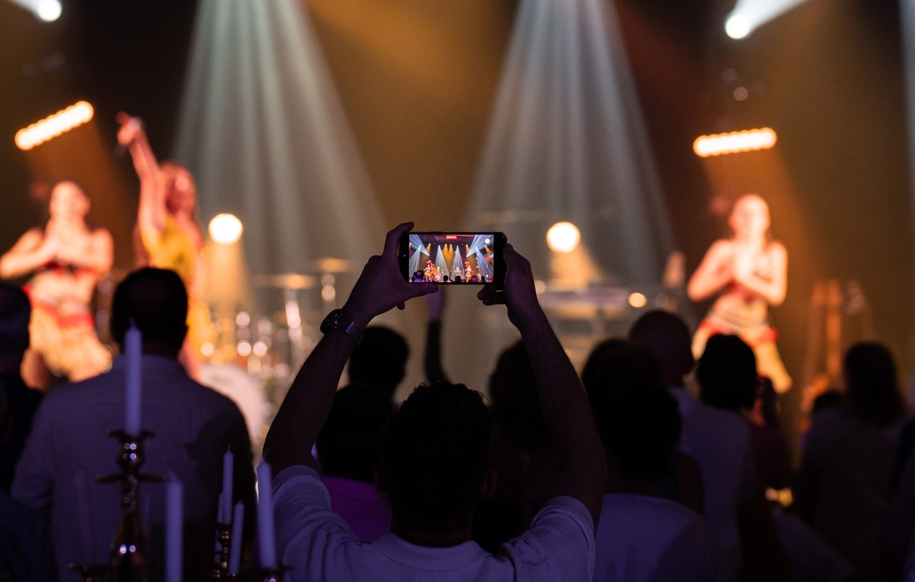 Public captivé, smartphones levés dans une salle plongée dans le noir