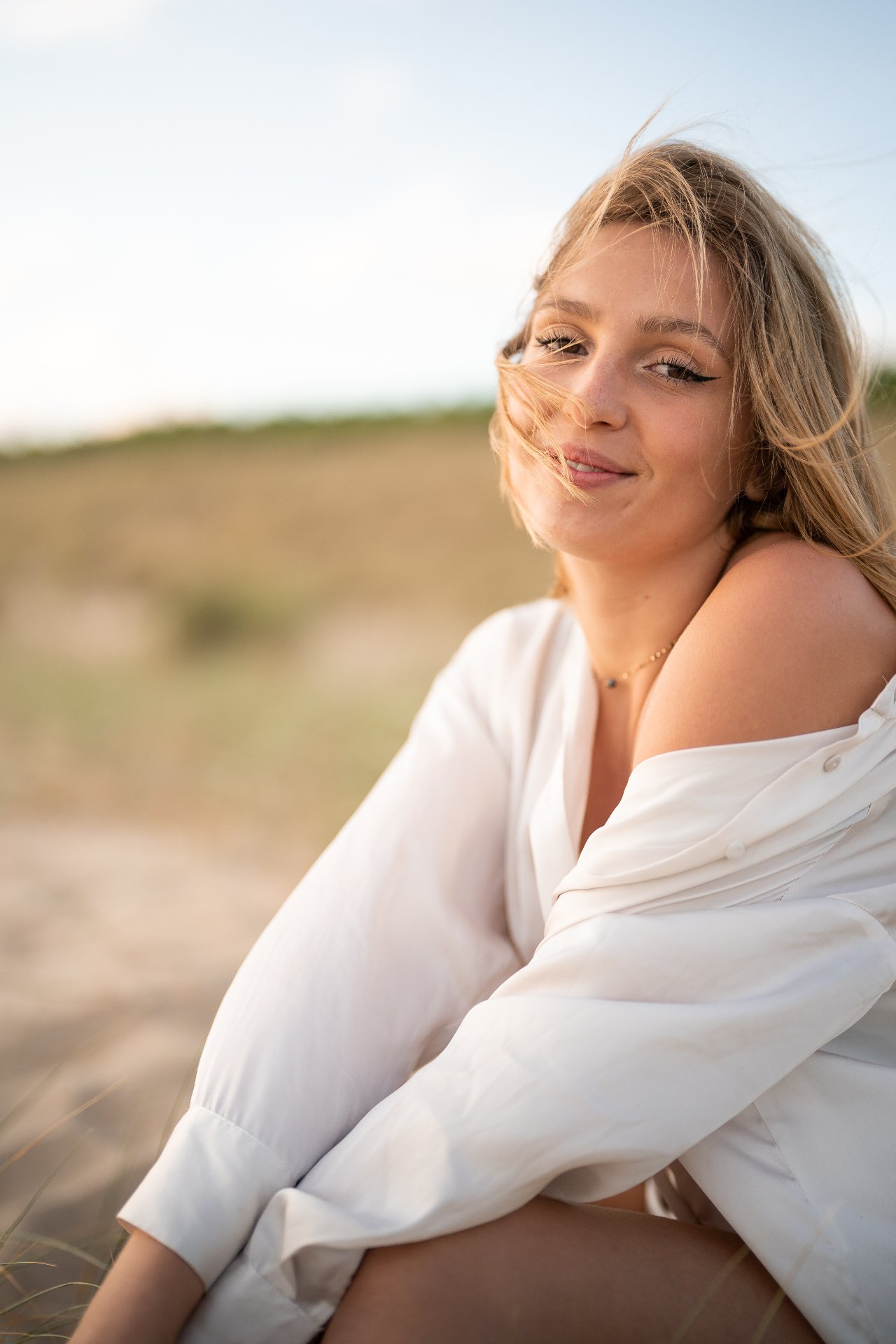 Portrait souriant d'une dirigeante dans les dunes, lumière naturelle de fin de journée