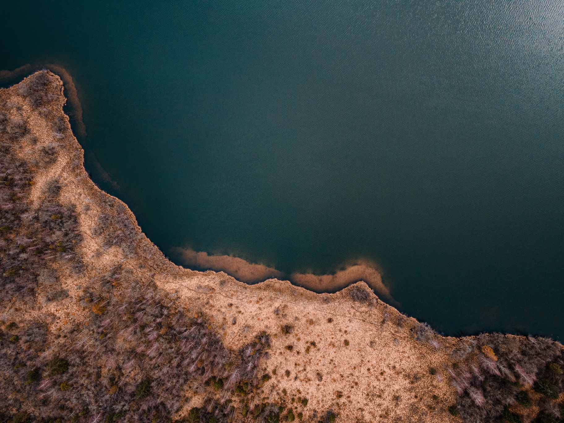 Rive abstraite d'un lac du Jura, sable et eau turquoise
