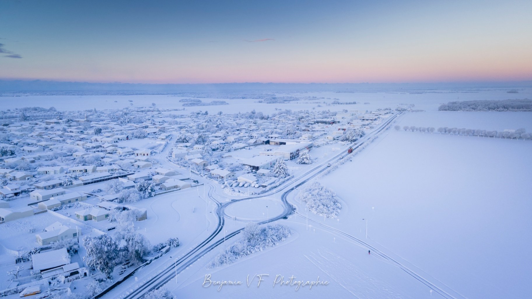 Village de Charente-Maritime sous la neige au drone, ciel rose pâle